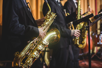 Concert view of a saxophonist, saxophone player with vocalist and musical during jazz band orchestra performing music on stage