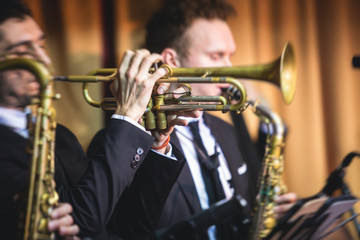 Concert view of a male trumpeter,  professional trumpet player with vocalist and musical during jazz band performing music