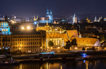 Fototapeta na wymiar A distant view of historic buildings in Old Town from across the Vltava River at night. 