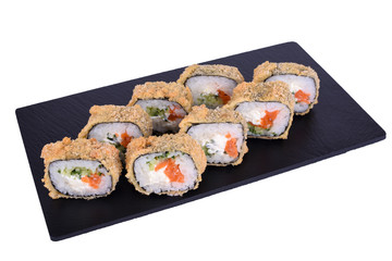 Traditional fresh japanese sushi on black stone Warm Salmon Roll on a white background. Roll ingredients: salmon, philadelphia cheese, cucumber, nori, rice, panko crackers.