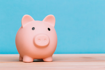 piggy bank on a wooden table and blue background. The concept of storage, accumulation and investment