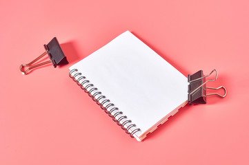 Blank paper notebook near binder on pink desk. Business concept