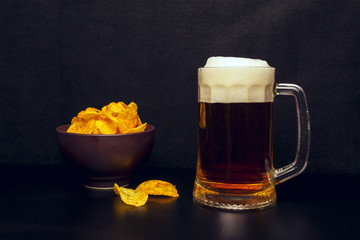 Chips in a clay plate and a glass of beer with foam