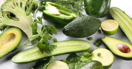 Green vegetables, fruits and herbs on a light background. Fresh pepper, zucchini, peas, cucumber, avocado, lime, broccoli, parsley, dill and spinach. Foodbackground. Background image