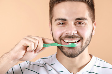 Happy smiling young man with tooth brush on color background