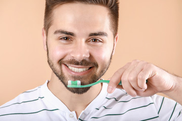 Happy smiling young man with tooth brush on color background