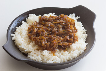 Close up caramelized onion with rice as garnish on black plate on the white background