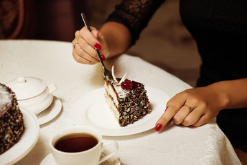 Appetite concept. Dessert cake cup of tea and female hand with fork close up. Piece of cake with red berry. Gourmet recipe food. Cake slice on white plate. Cake with cream delicious dessert.