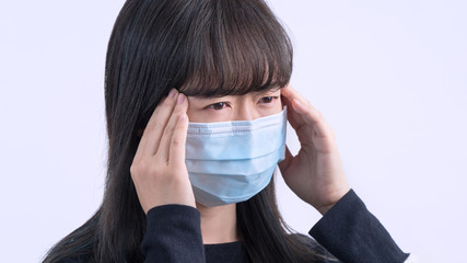 Young woman is feeling dizzy, headache, sick, unwell with wearing a medical blue face mask over the...