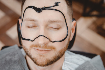 Acne removal with cosmetic product, cleaning pores of men skin, barber applying black charcoal mask...