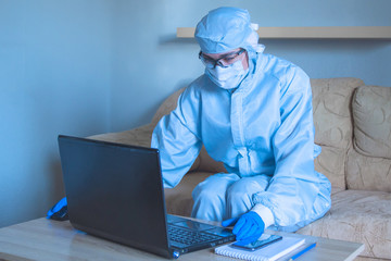 Work from home with laptop under social distancing and self isolation due to covid-19 virus. Online education and remote freelance work during quarantine.Specialist working protective suit 