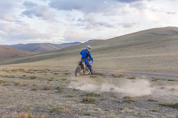 Obraz premium Man riding a motorbike in the steppes of Mongolia, on the hills of Mongolia