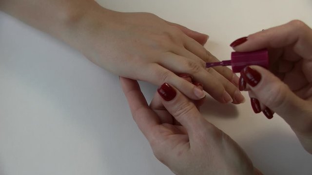 a woman paints her nails with nail Polish