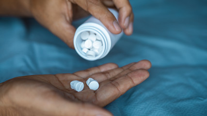 Man hand pouring tablets pills into hand