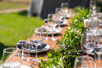 Beautifully decorated wooden table in a summer open-air cafe. Green branch and fresh flowers table decoration