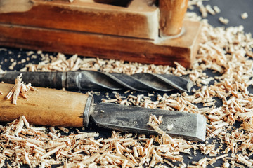 Old hand plane, drill and chisel with wooden shavings on black background. Old woodworking hand tool. Copy, empty space for text