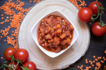 vegane Nudelsoße a la Bolognese aus roten Linsen, Tomaten und Möhren auf schwarzen Untergrund aus Holz