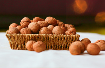 Walnuts on the rough in a wicker basket on a white background.  Glare in the background. Healthy eating concept