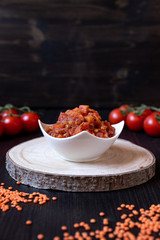 vegane Nudelsoße a la Bolognese aus roten Linsen, Tomaten und Möhren auf schwarzen Untergrund aus Holz