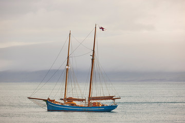 Yacht sailing on Faroe island fjords. Atlantic ocean coastline. Denmark