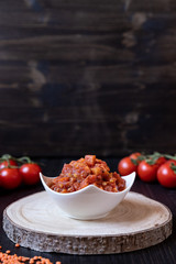 vegane Nudelsoße a la Bolognese aus roten Linsen, Tomaten und Möhren auf schwarzen Untergrund aus Holz
