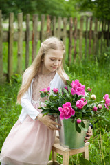 Beautiful little blonde girl with metal bucket with peonies