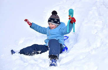 Fototapeta na wymiar Child to have fun in the winter outdoors. Fun kid boy in the snow. A winter vacation. Boy slide down the hills.