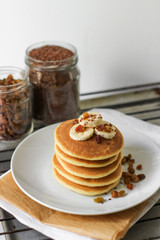 Homemade pancakes with banana for breakfast. Containers with ingredients on background