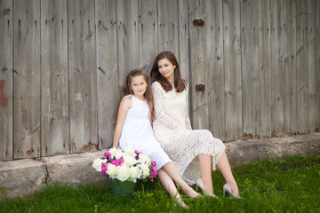 Beautiful girl with a young woman in a white dress with peonies