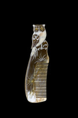 Natural horn engraved comb owl pattern isolated on black background.