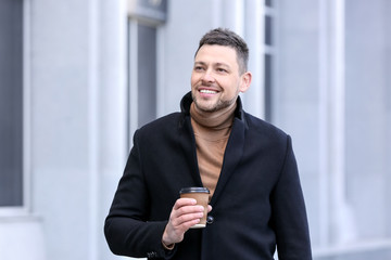 Handsome man with cup of coffee outdoors