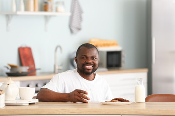 African-American man drinking milk in kitchen