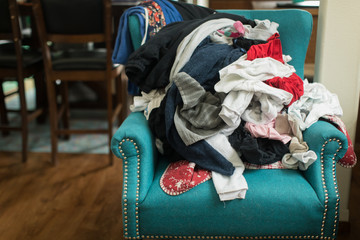 Pile of laundry of clothes on colorful chair in home