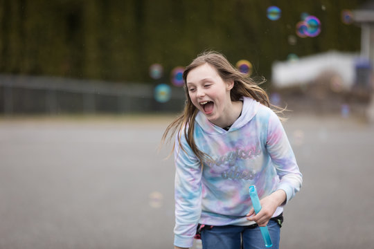 Happy pre-teen girl playing outside with colorful bubbles