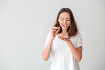 Beautiful young woman eating tasty chocolate candies on white background