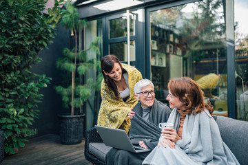 Fototapeta premium Happy family time. Three women of different age relaxing at modern home garden.