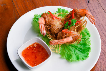 Goong Sarong  noodles Wrapped Shrimp With Crispy Noodle Serve, vegetable and sauce in white plate  on wood table , Thai food