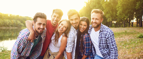 Group of friends cuddling while standing at a nature party. Young people have fun on a picnic.