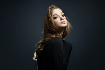 Beauty portrait blonde woman with makeup and big blue eyes, natural cosmetics, clean delicate skin of the girl face, black clothes. Drops of makeup trickle from the girl eyes