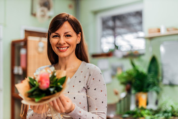 Portrait of a beautiful woman at florist shop, holding fresh flower bouquet, close-up.