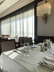 Set tables with silverware and glasses in formal dining room or restaurant on Azamara Club Cruises...