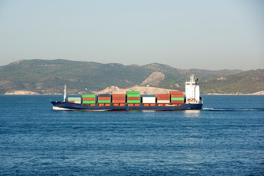 Log&iacute;stica y carga de contenedores por grandes barcazas por mar en un puerto lleno de contenedores que esperan ser transportados