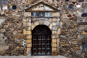 Fototapeta na wymiar Old entrance gate in the wall of wild stone.
