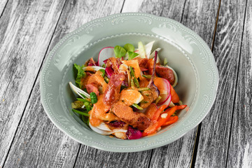 Vegetable salad with sausages in a plate on an isolated background