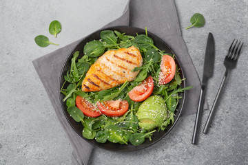 Keto diet. Grilled chicken breast, arugula, spinach, avocado and tomatoes. Top view.