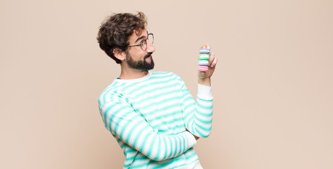 young man with macaroons against flat wall