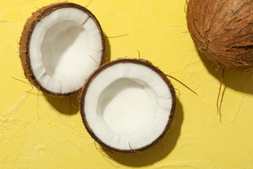 Coconut on yellow background, top view. Tropical fruit