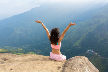 Girl enjoys a mountain view while standing on a cliff