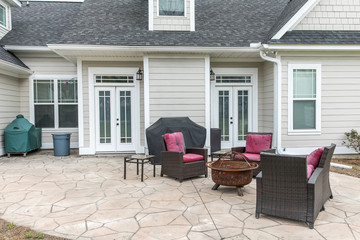 The back rear view of a new construction home with a covered up barbecue and patio furniture with a...