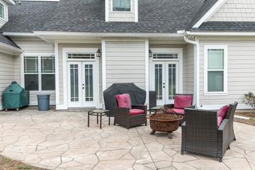 The back rear view of a new construction home with a covered up barbecue and patio furniture with a stamped concrete patio floor